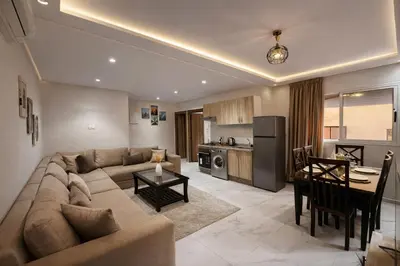 a living room with a couch and a table and a kitchen at Studio Chic & Haut Standing - Parking Gratuit in Marrakech