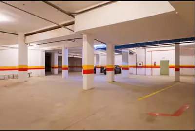 an empty parking garage with white columns and red and yellow stripes at gueliz central & Moderne in Tamazouzte