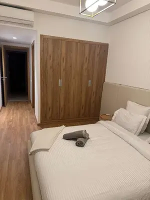 a bedroom with a large white bed and a wooden cabinet at Luxury Noria Apartment - Pool - Security - airport in Oulad Akkou