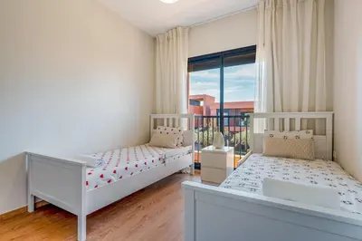 a bedroom with two beds and a large window at Amal Cozy - Modern Design, 4 Pools & HD Wifi in Marrakech