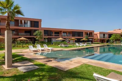 a swimming pool with lounge chairs and a building at Amal Cozy - Modern Design, 4 Pools & HD Wifi in Marrakech