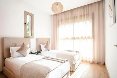 two beds in a white room with a window at The Calm Haven - Marrakech - Prestigia in Marrakech