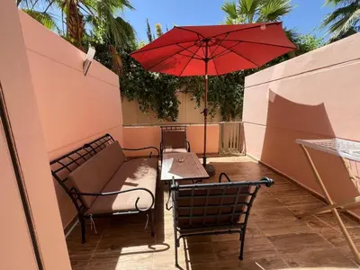 a patio with a table and a red umbrella at Elegant duplex Marrakech in Marrakech