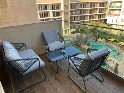 a balcony with chairs and a table and a pool at Modern apartment with pool view, Kech in Marrakech