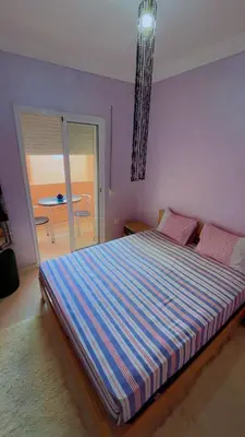 a bedroom with a large bed with a striped blanket at Apartment near Mènera gardens and city center in Marrakech
