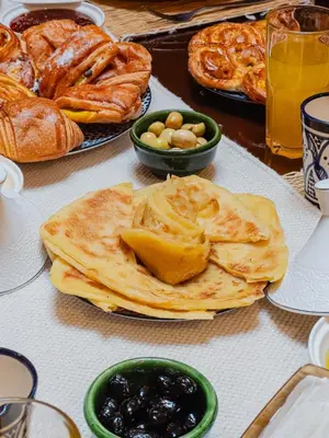 a table topped with plates of bread and pastries at Riad Marrakech Red Ruby in Marrakech
