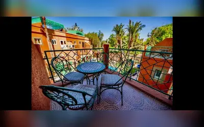 a balcony with a table and chairs on a balcony at Riad Marrakech Red Ruby in Marrakech