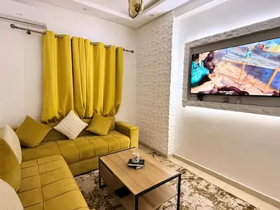 a living room with a yellow couch and a flat screen tv at Appartement Cosy and Calme Proche Centre Marrakech in Marrakech