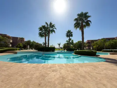 a large swimming pool with palm trees in the background at Prestigia 3 Bedrooms witch pool and Garden in Marrakech