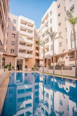 a swimming pool in front of some apartment buildings at Appartement Moderne & Cosy Proche Centre Piscine, Wi-Fi Haut Débit & Netflix Marrakech in Marrakech