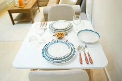 a white table with blue and white plates and silverware at Appartement Moderne & Cosy Proche Centre Piscine, Wi-Fi Haut Débit & Netflix Marrakech in Marrakech