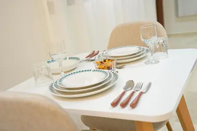 a white table with plates and silverware on it at Appartement Moderne & Cosy Proche Centre Piscine, Wi-Fi Haut Débit & Netflix Marrakech in Marrakech