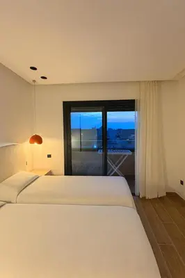 a bedroom with two beds and a large window at Aube d hivernage Marrakech in Marrakech