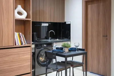 a kitchen with a washing machine and a table with wine glasses at Appartement Chic M Avenue, Balcon, Piscine, Parking Wi-Fi Haut Débit Marrakech in Marrakech