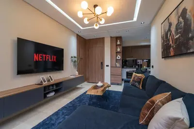 a living room with a blue couch and a tv at Appartement Chic M Avenue, Balcon, Piscine, Parking Wi-Fi Haut Débit Marrakech in Marrakech