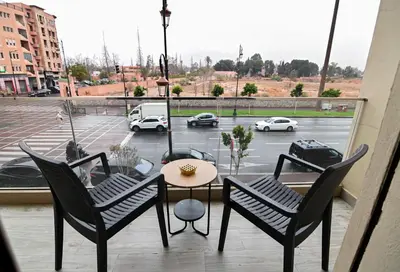 a balcony with a table and chairs and a view of a parking lot at Downtown Prestige 2Br apartment cinema AC in Marrakech