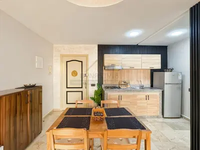 a kitchen with a table and chairs and a refrigerator at Confort Moderne au Cœur de Marrakech Proche Gare in Marrakech