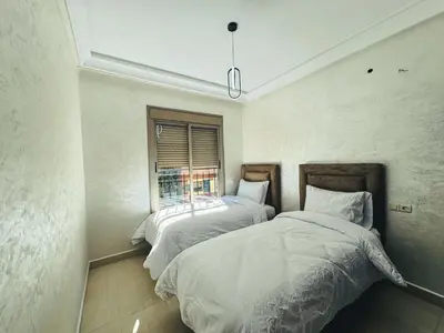 two beds in a room with a window at Al Waha Prestige Apartment in Marrakech