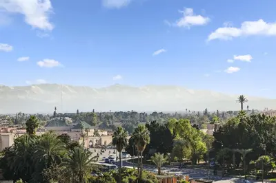 a city with palm trees and mountains in the background at Centre Town Cozy Apartment with Panoramic View in Marrakech
