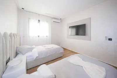 a white bedroom with two beds and a tv at Modern apartments, cozy residence, swimming pools in Marrakech