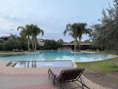 a large swimming pool with a table and chairs in it at Cozy Flat , Resort-Style Pool ,10 min to Center in Marrakech