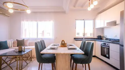 a kitchen and living room with a table and chairs at Appartement Chic avec Piscine au Cœur de Gueliz in Marrakech