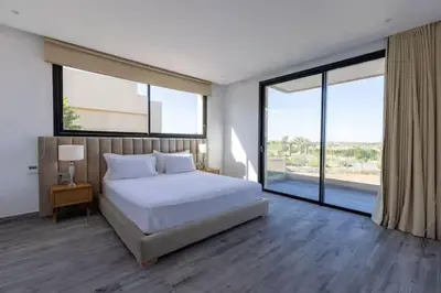 a bedroom with a white bed and large windows at Momiji Golf Villa - Private Heated Pool in Marrakech