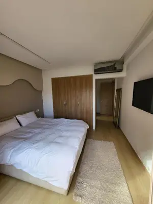 a bedroom with a white bed and a flat screen tv at Luxury Apartment Les Cerisiers Marrakech in Marrakech