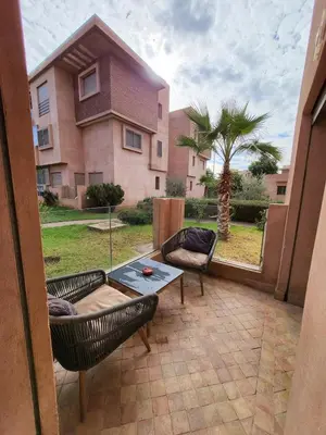 a patio with a table and chairs in front of a house at Luxury Apartment Les Cerisiers Marrakech in Marrakech