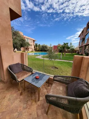a patio with a table and chairs and a view of a pool at Luxury Apartment Les Cerisiers Marrakech in Marrakech