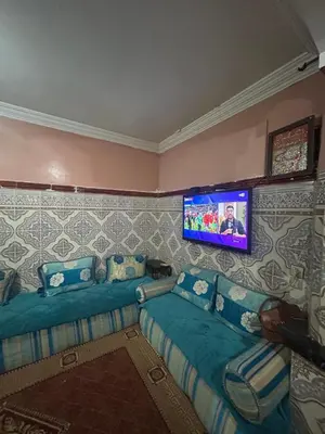 a living room with two beds and a flat screen tv at Maison confortable pour familles in Zaouia El Hedil Mamra