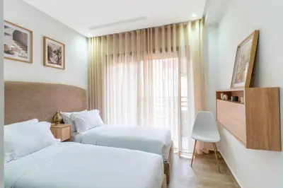a hotel room with two beds and a window at Menara Suite Harmonie , Terrasse et Piscine in Marrakech