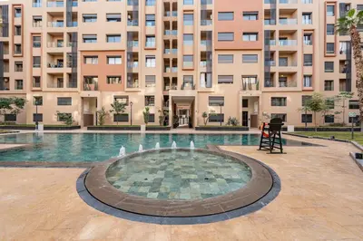 a swimming pool with a fountain in front of a building at Le Lotus - Piscine intérieur et extérieur - Wifi - Fitness in Marrakech
