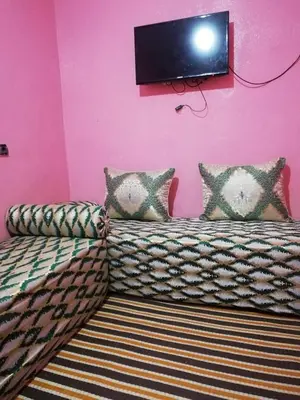 a room with a couch and a tv on a pink wall at famile 154 in Marrakech