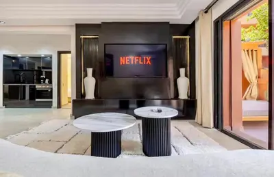 a living room with two tables in front of a tv at Simone moves to Guéliz in Marrakech