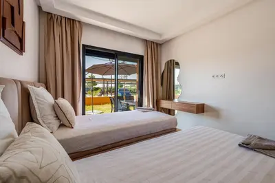 a bedroom with two beds and a window with an umbrella at Noria Golf Marrakech pool view 2 bedrooms garden in Marrakech