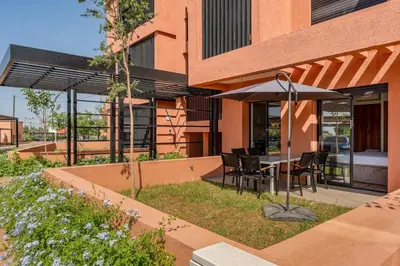 an outdoor patio with a table and an umbrella at Noria Golf Marrakech pool view 2 bedrooms garden in Marrakech