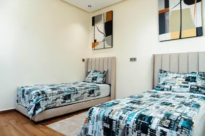 a bedroom with two beds and paintings on the wall at Appartement moderne in Marrakech