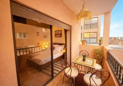 a balcony with a bed and a table and chairs at Andalous Prestige in Marrakech
