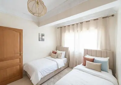 a bedroom with two beds and a window at Andalous Prestige in Marrakech