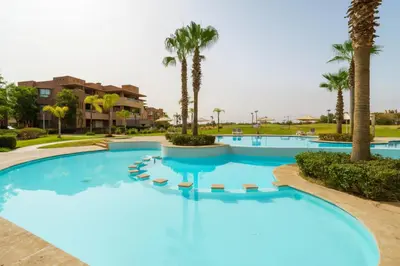 a large swimming pool with palm trees in a resort at Prestigia Golf View - Piscine & terrasse in Marrakech