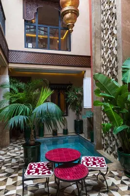 a pool with four tables and chairs in front of a building at Riad Dar Shala in Marrakech