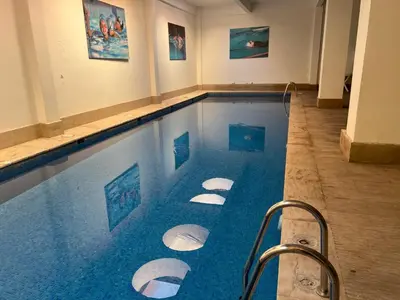 a swimming pool with blue water in a building at Le petit cocon in Marrakech