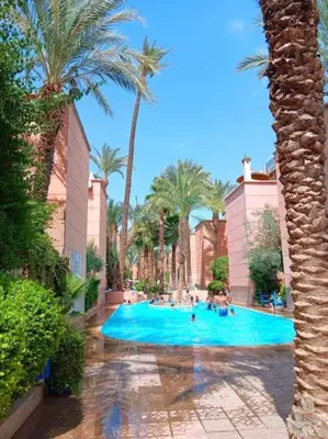 a swimming pool with palm trees and people in it at Riad Marrakech Golden Star 82 with 3 Rooms & Pool in Marrakech