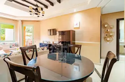 a dining room and living room with a table and chairs at Appartement marrakech garden in Marrakech