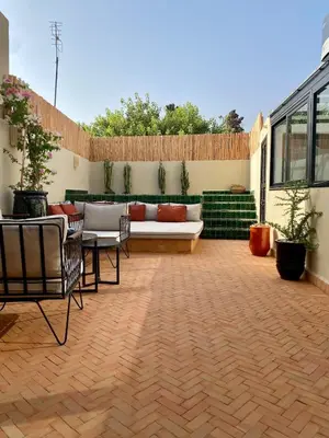 a patio with a couch and a table and chairs at Riad Costa 2 privates pools rooftop breakfast in Marrakech