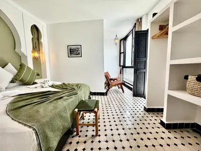 a bedroom with a bed and a chair in a room at Riad Costa 2 privates pools rooftop breakfast in Marrakech