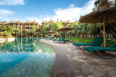 a resort swimming pool with chairs and umbrellas at Appartement de charme avec piscine a Marrakech in Marrakech
