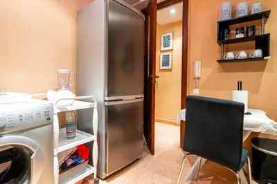 a kitchen with a stainless steel refrigerator and a chair at Appartement de charme avec piscine a Marrakech in Marrakech