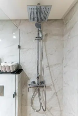 a shower in a bathroom with white marble walls at Bright & Chic Stay in Marrakech Gueliz in Marrakech